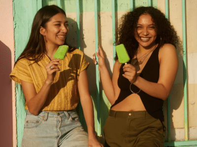 Two young women holding ice creams in front of a building.