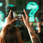 A woman taking a picture of a crowd at a concert.
