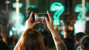 A woman taking a picture of a crowd at a concert.