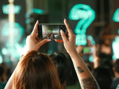 A woman taking a picture of a crowd at a concert.