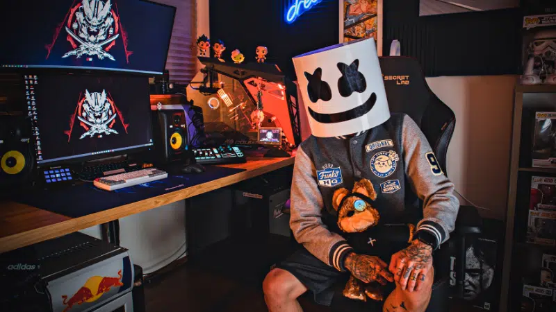 A man sitting in front of a computer wearing a marshmallow mask.