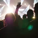 A crowd at a concert with their hands raised.