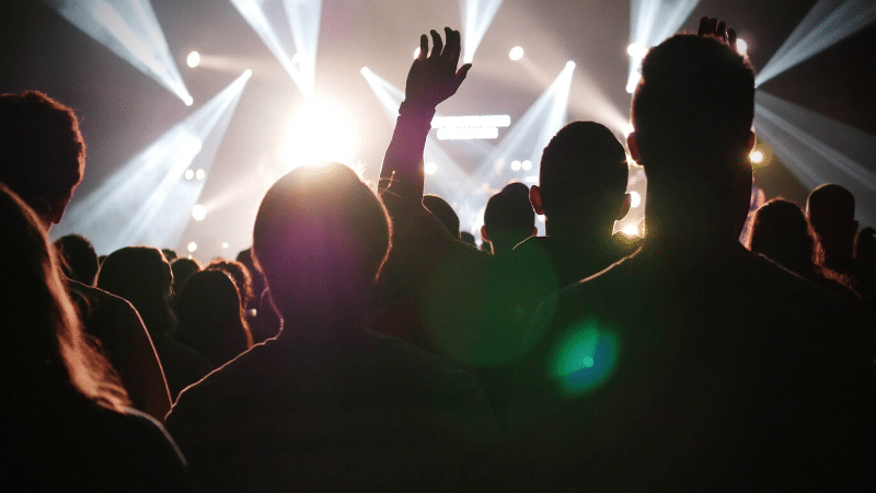 A crowd at a concert with their hands raised.