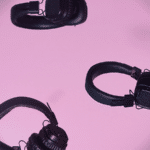 A group of black headphones on a pink background.