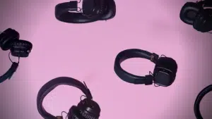 A group of black headphones on a pink background.