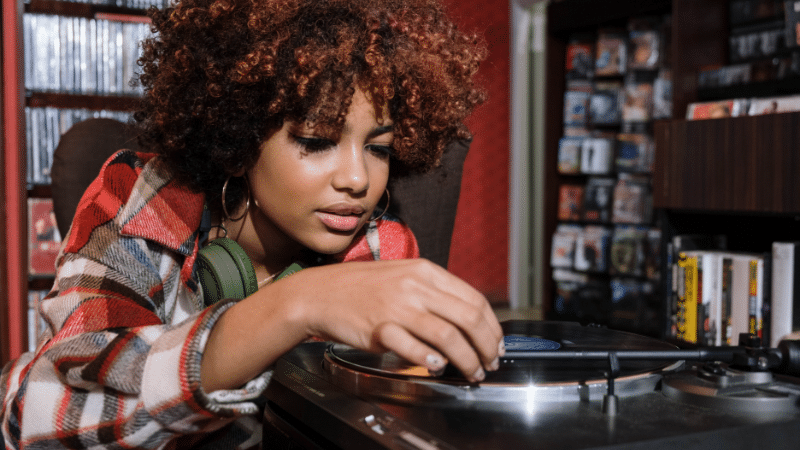 A young woman browsing through a turntable in a music store, searching for the perfect gift for musicians.