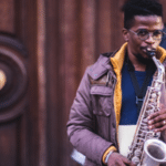 Young man, saxophone, wooden door.