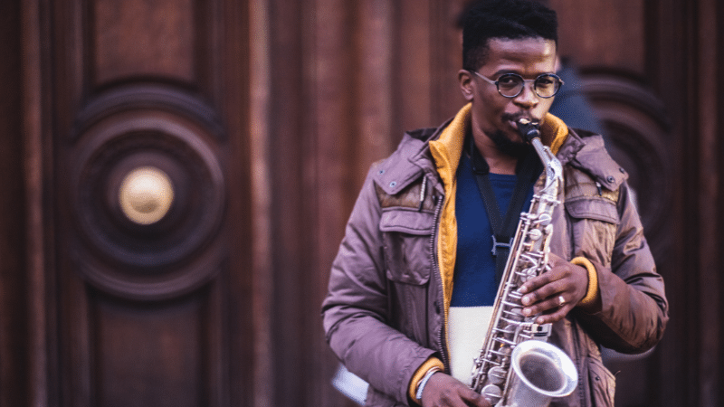 Young man, saxophone, wooden door.