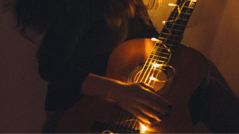 A woman playing a guitar in a dark room.