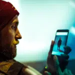 A man wearing a beanie looking at his phone.