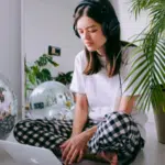 A woman wearing headphones and sitting on the floor with a laptop, utilizing productivity tools.