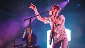 A man singing into a microphone at SXSW concert.