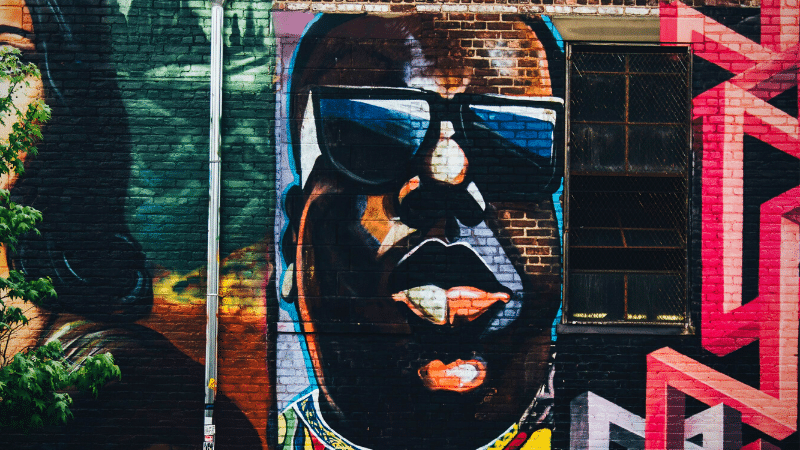 Graffiti on a building with a woman in sunglasses. (Keywords: graffiti, woman)