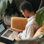 A couple engaged in marketing activities on a couch using a laptop.