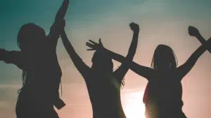 Silhouette of a group of empowered women celebrating at sunset.