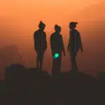 Three empowered women standing on top of a mountain at sunset.