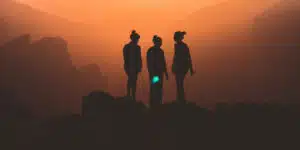 Three empowered women standing on top of a mountain at sunset.