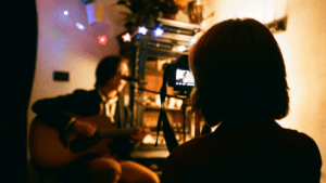 A person capturing an acoustic guitarist's performance for Instagram Reels.