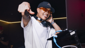 A man on a tour is pointing at a DJ.