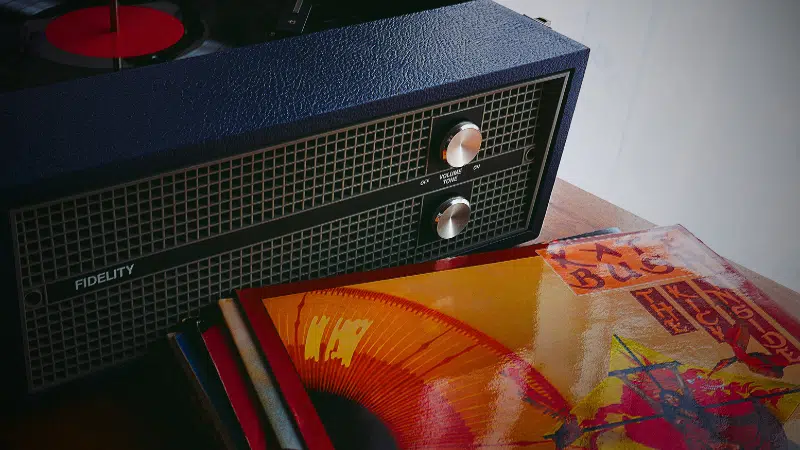 A vinyl record player sits on a table next to a stack of records.