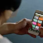 A person holding a cell phone with a Spotify app.