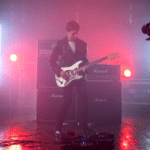 A man is playing an electric guitar in a dark room, video.