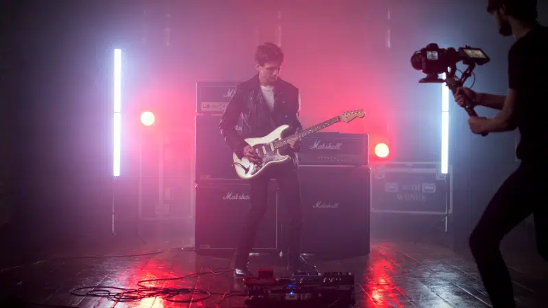 A man is playing an electric guitar in a dark room, video.