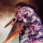 A man in a floral shirt singing into a microphone, showcasing AAPI artistry.