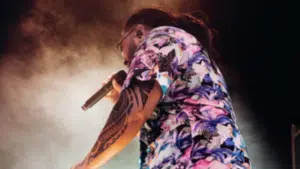 A man in a floral shirt singing into a microphone, showcasing AAPI artistry.