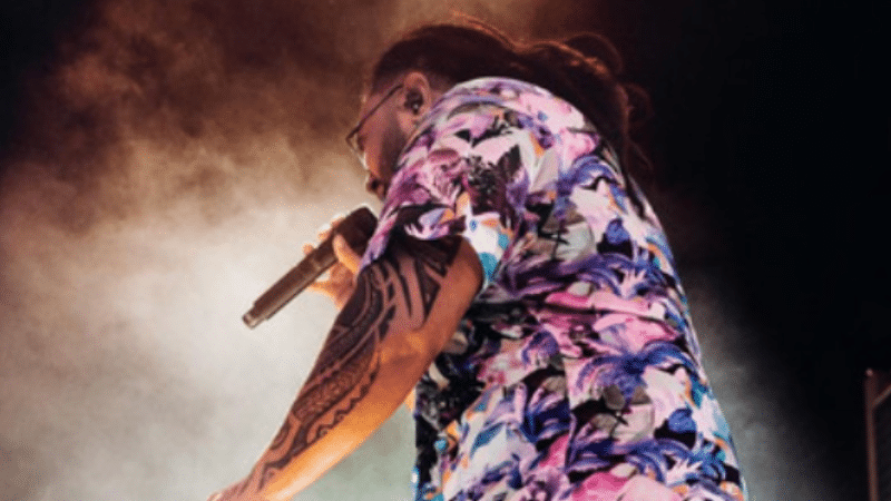 A man in a floral shirt singing into a microphone, showcasing AAPI artistry.