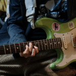 A person playing a synchronized green electric guitar.