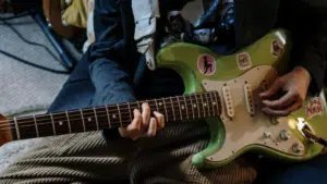 A person playing a synchronized green electric guitar.