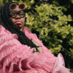 A black artist painting a woman in a pink dress.