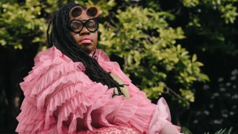 A black artist painting a woman in a pink dress.