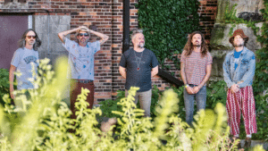 A group of men performing fresh new music in front of a brick building.