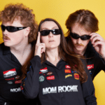 Three individuals in sunglasses showcasing fresh new music on a yellow background.