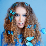 A young woman with fresh blue butterflies on her hair.