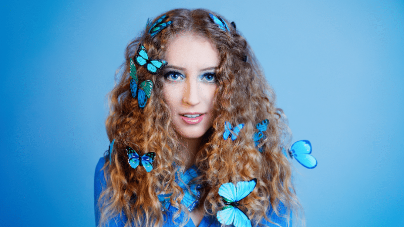 A young woman with fresh blue butterflies on her hair.