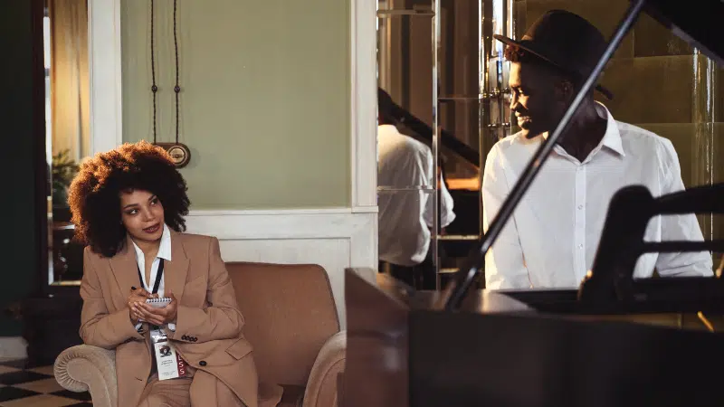 woman interviewing musician sitting at piano