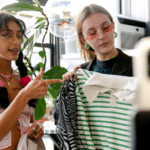 Two women engaging in influencer marketing while looking at a shirt in a store.