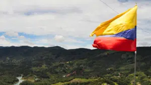 A yellow, blue, and red flag waves against a backdrop of green hills and a cloudy sky, like a banner heralding a grand conference in unity’s colors.