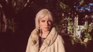 A fresh woman in a white coat standing in a yard.