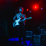 A man playing a guitar on a Nashville stage.