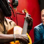 man playing guitar with woman on street