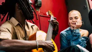 man playing guitar with woman on street