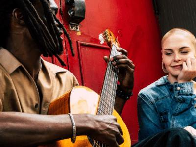 man playing guitar with woman on street