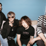 A group of men posing for a picture on a couch while enjoying fresh new music.