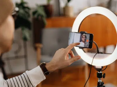 A man is taking a TikTok video with a ring light.