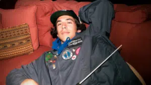 A man laying on a couch with a baseball bat, portrayed by indigenous artists.