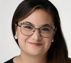 A woman wearing glasses smiles in front of a white background, representing SoundExchange.